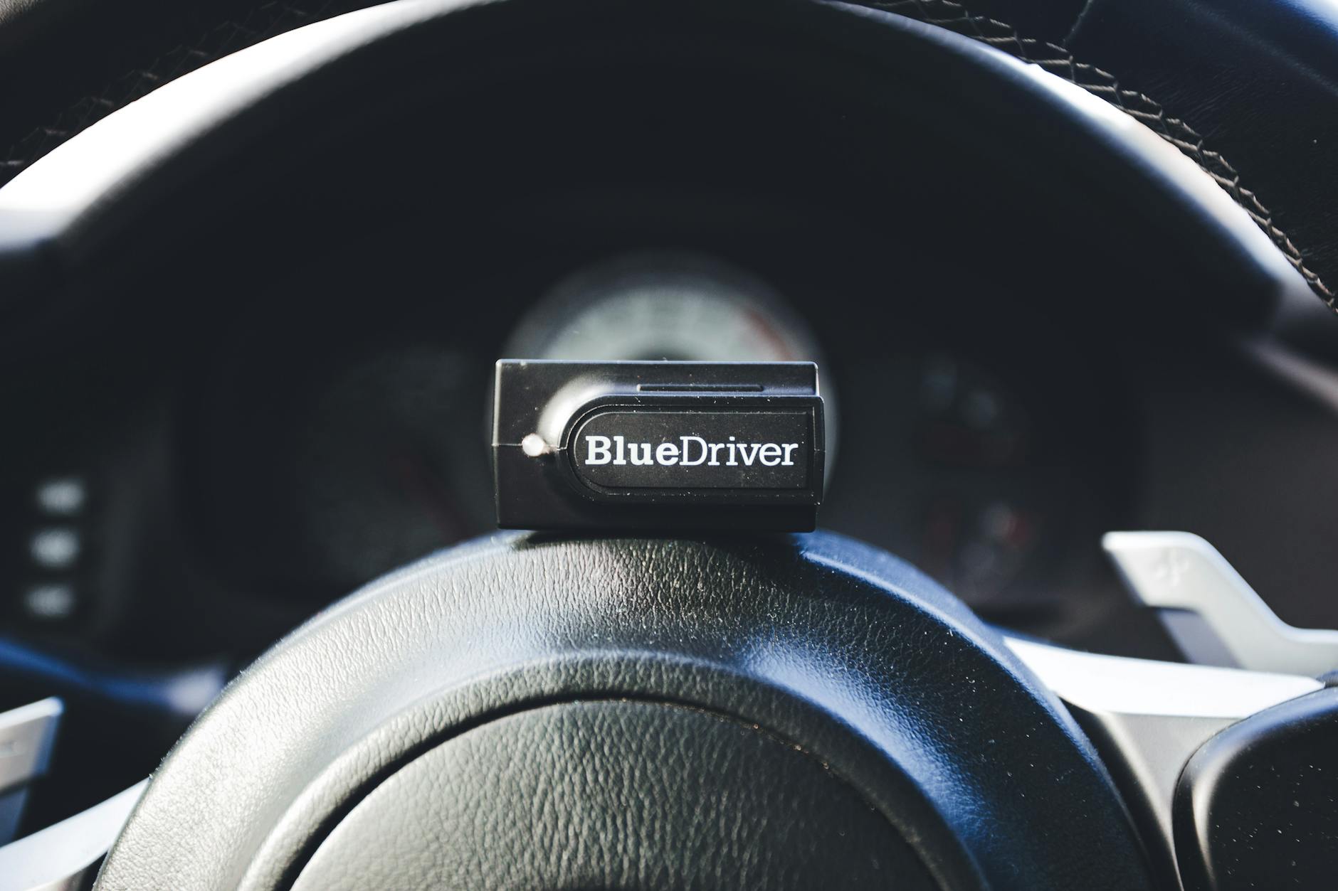 Tester diagnostyczny BlueDriver na kierownicy samochodu w kabinie