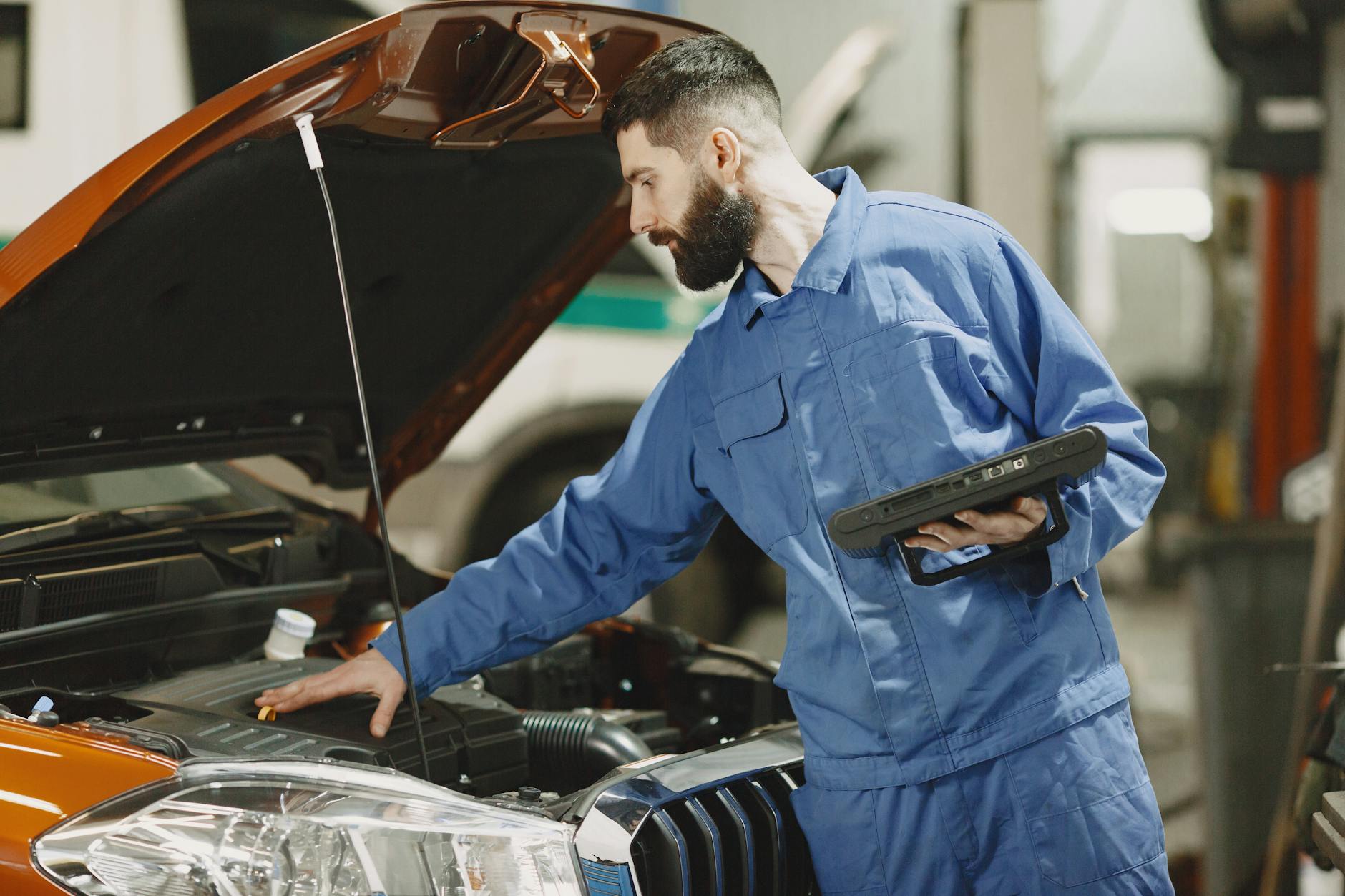 Mechanik sprawdza silnik auta pod kątem nieszczelności w garażu