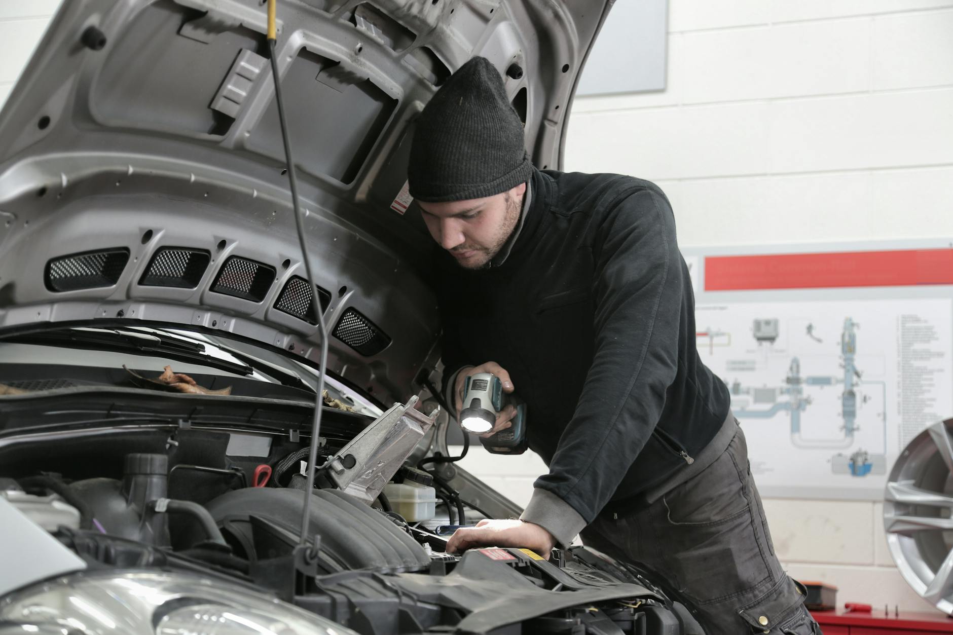 Mechanik z latarką sprawdza silnik auta w warsztacie