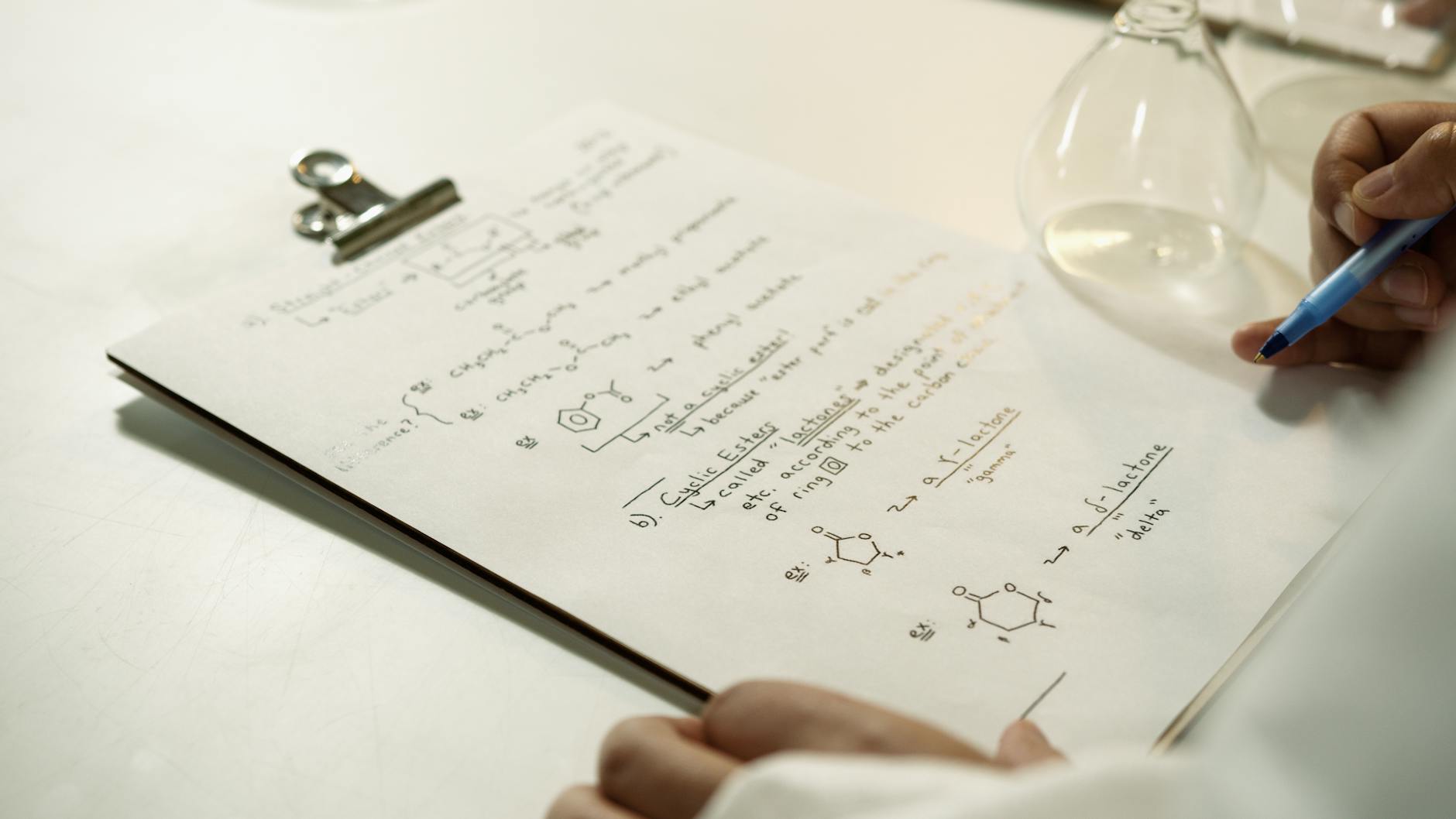 Notatki z równaniami chemicznymi na clipboardzie w laboratorium