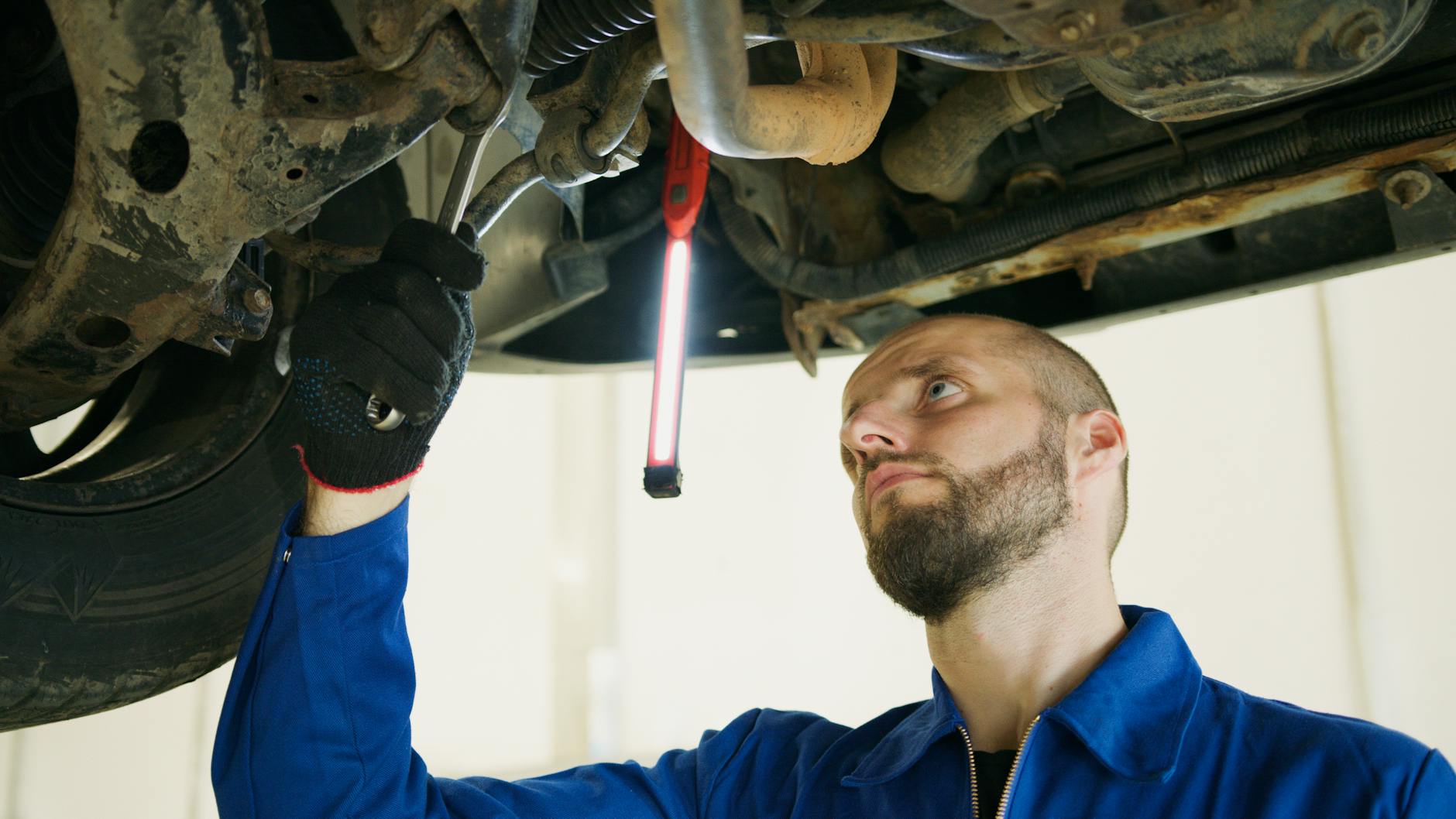 Mechanik diagnozuje zawieszenie samochodu na podnośniku w warsztacie