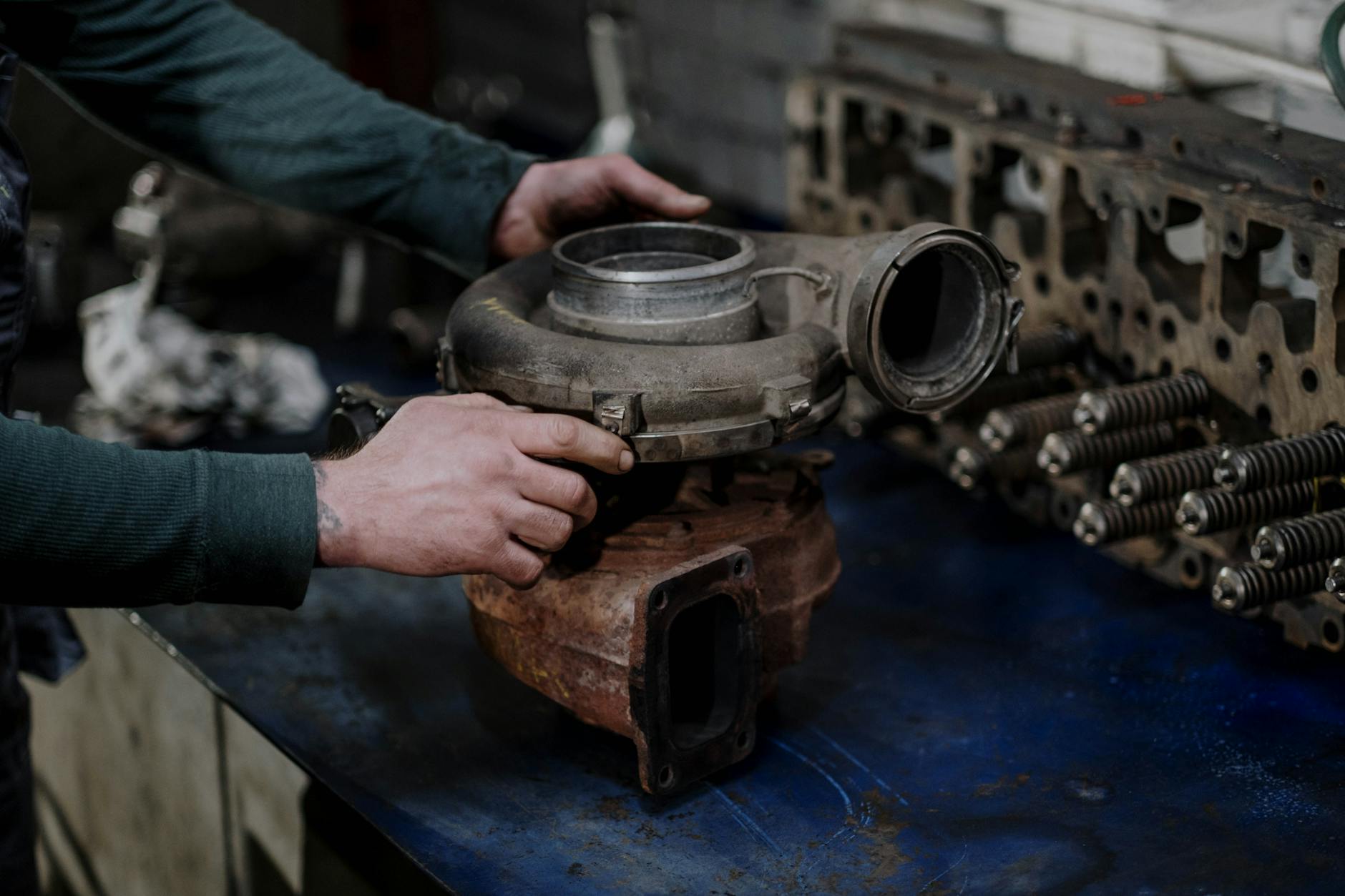 Mechanik naprawiający turbosprężarkę na stole w warsztacie