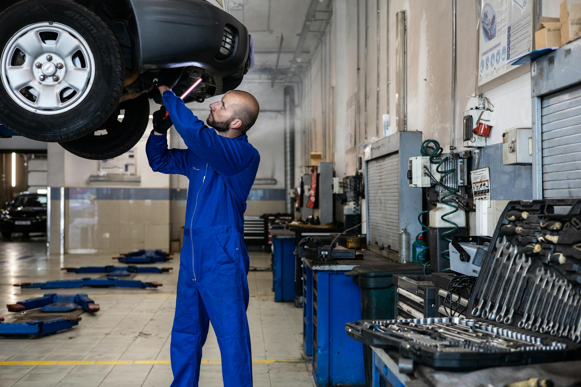 Mechanik ogląda zawieszenie pod uniesionym samochodem w warsztacie