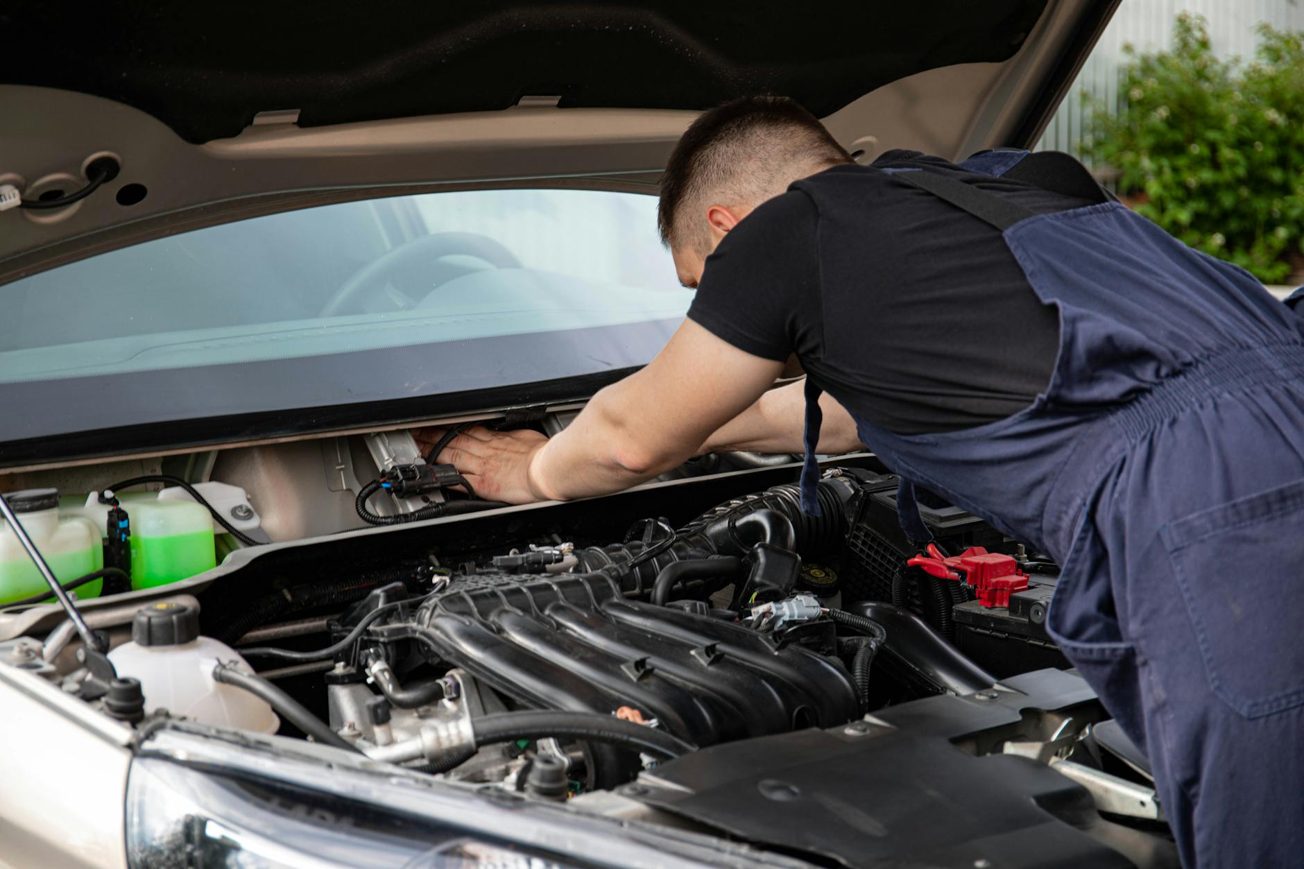 Mechanik sprawdza silnik samochodu, zbliżenie na dłonie i podzespoły